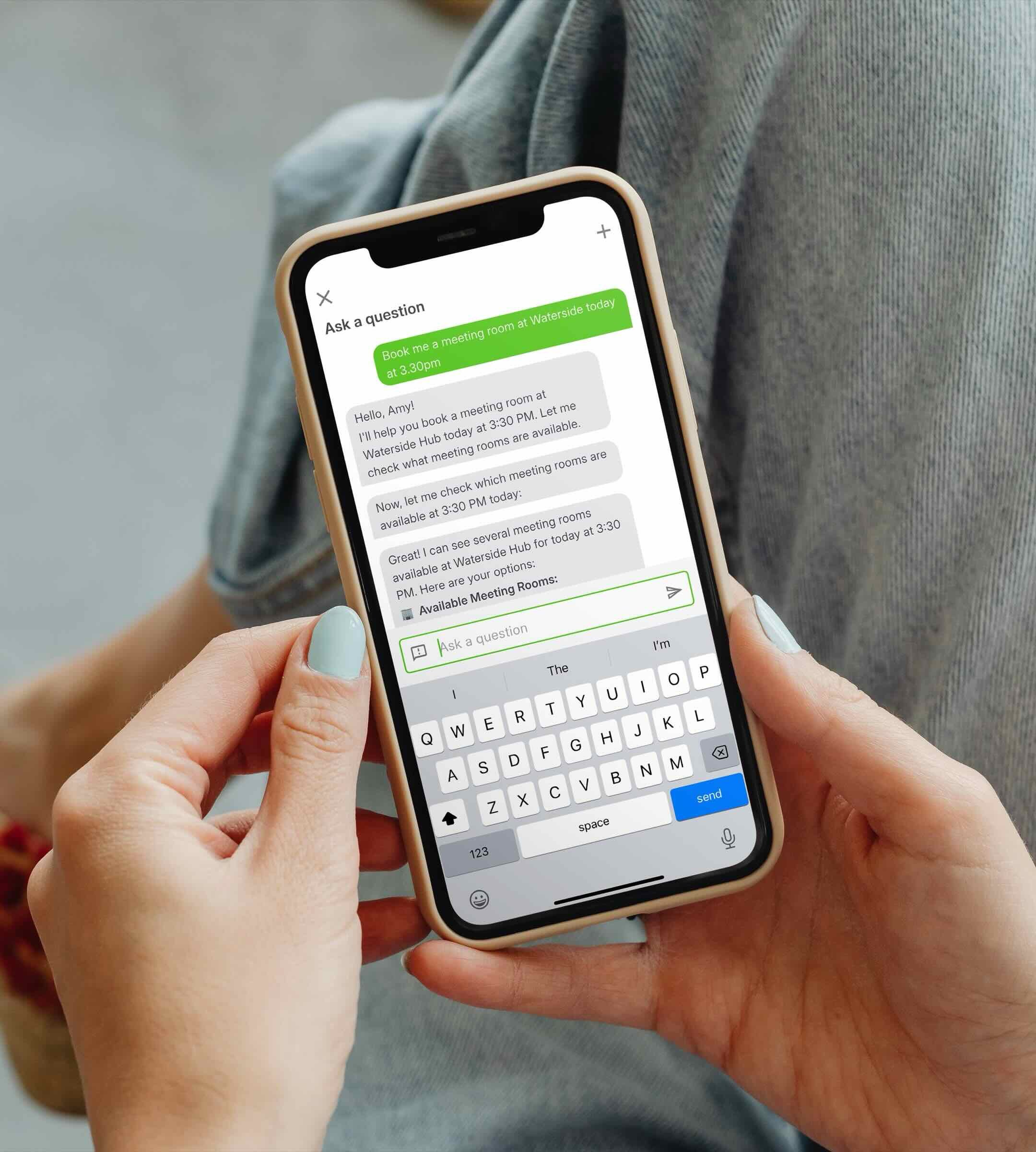 A person holds a smartphone displaying a conversation with a virtual assistant, Sign In App's AI Companion Assistant. The screen shows booking a meeting room at 3:30 PM.
