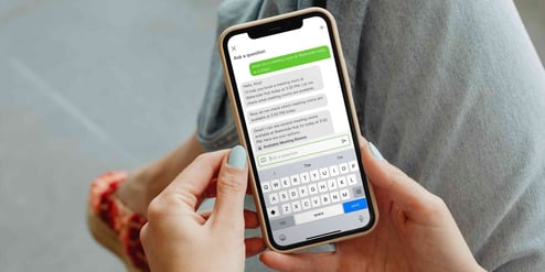 A birds-eye view photo of someone on an iPhone and on the iPhone screen is the AI assistant chat in visitor management system, Sign In App's, Companion App